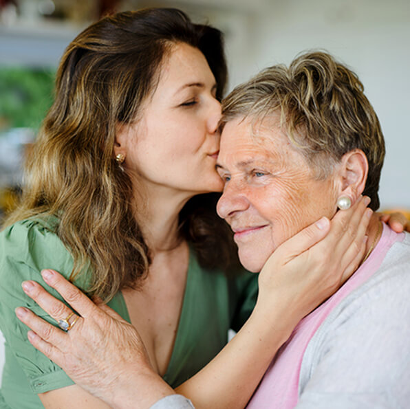 A young woman embraces an elderly woman